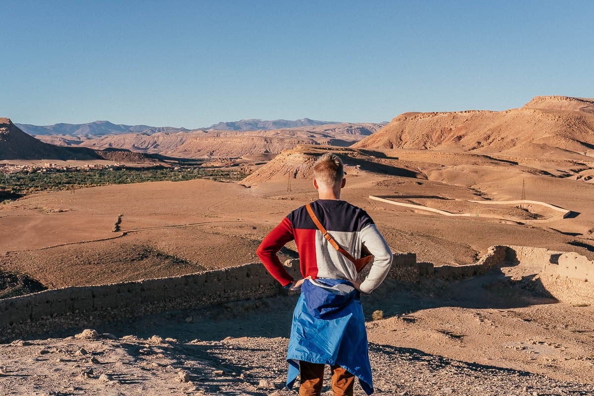 Czerwona, jałowa ziemia jest otoczona majestatycznymi górami w oddali.