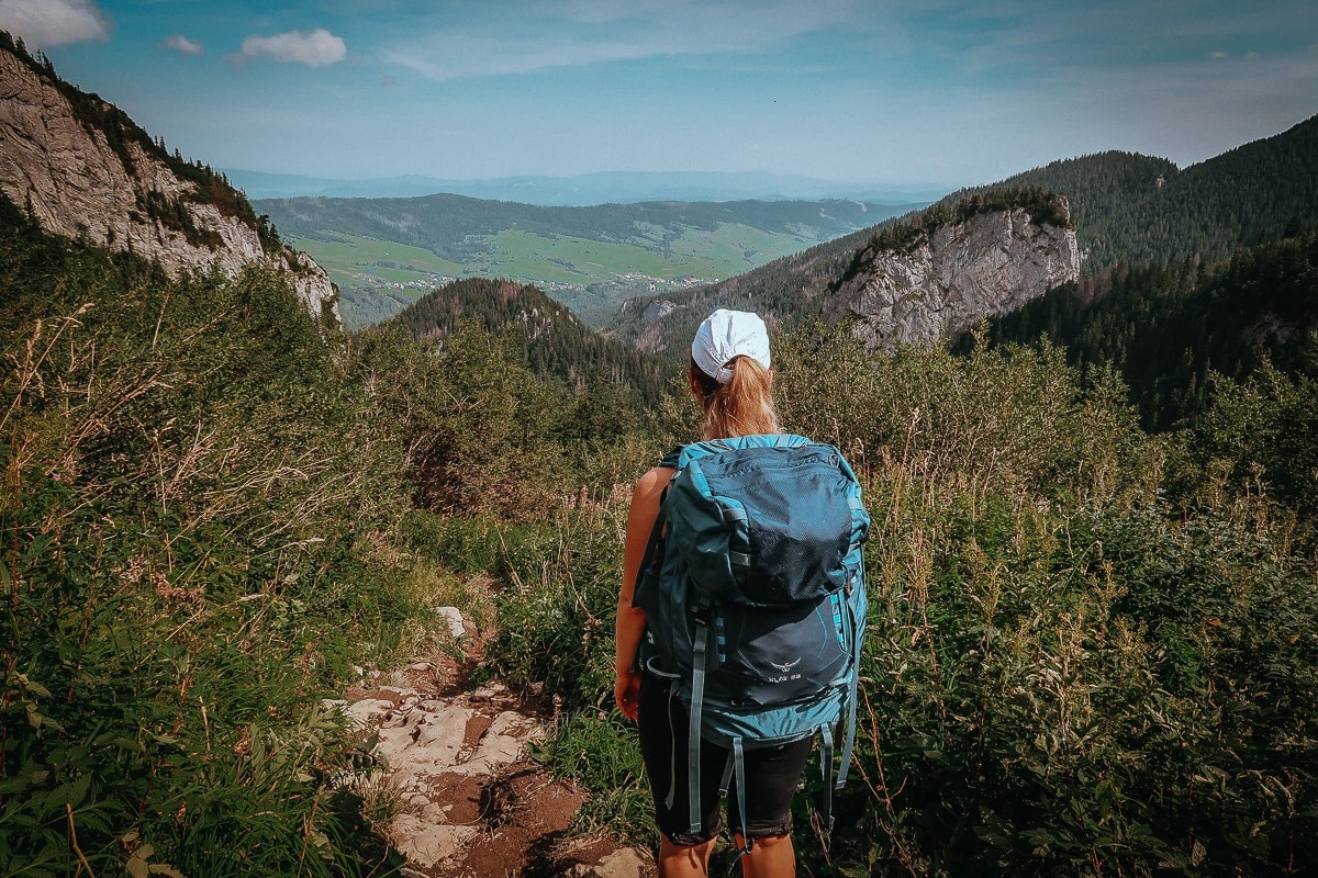 Wanderin mit großem Rucksack auf einem Hügel mit Blick ins Tal der Belianské Tatry